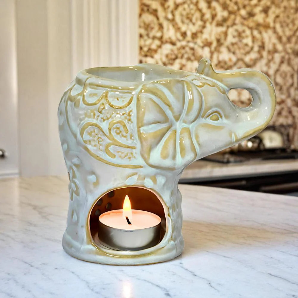Ceramic elephant-shaped candle holder with a lit tealight candle on a marble surface.