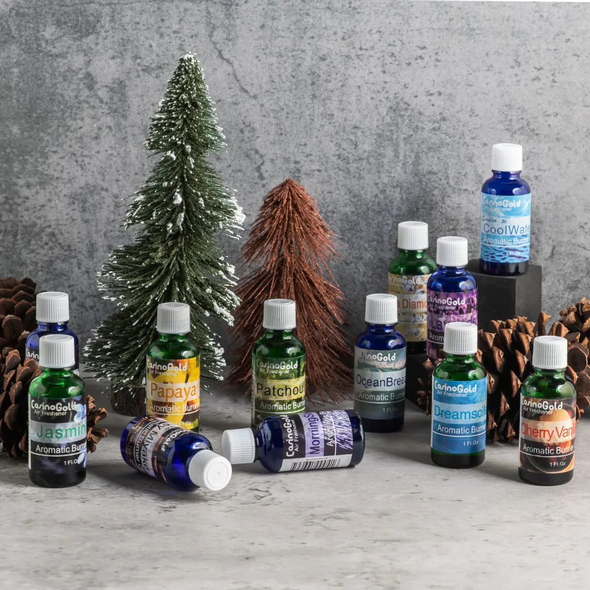 Winter holiday-themed display of Casino Gold fragrance oils with mini Christmas trees and pinecones